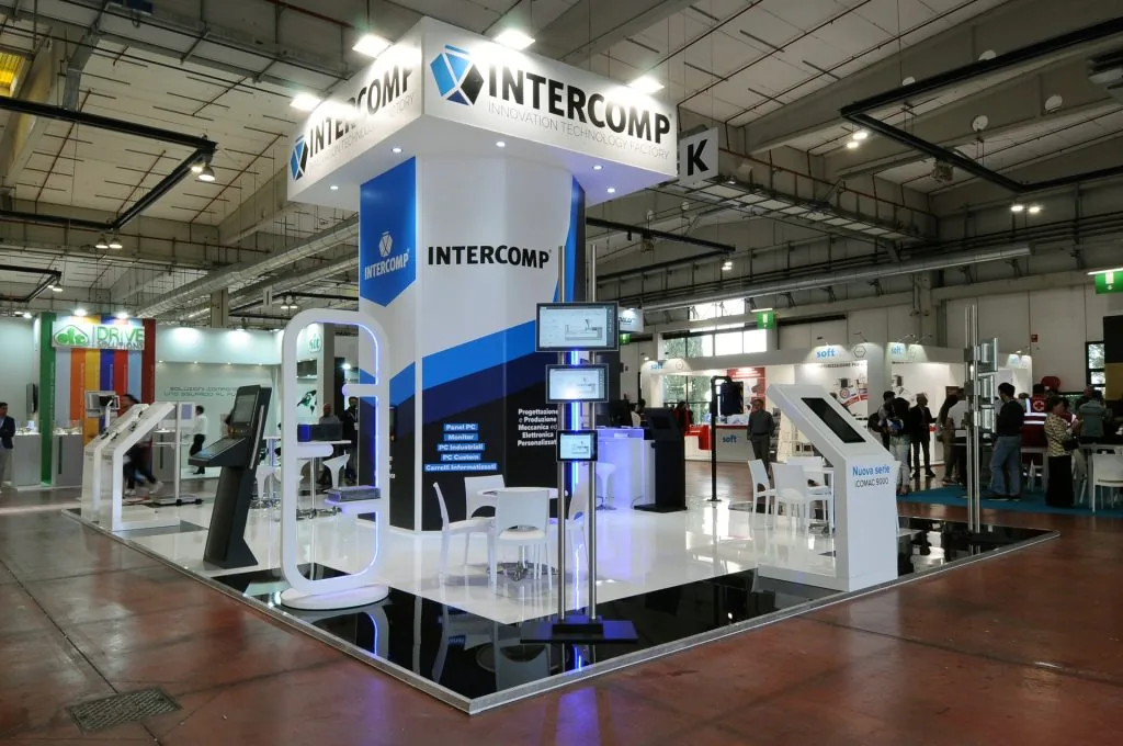 Stand espositivo INTERCOMP a una fiera tecnologica, con design moderno, schermi digitali e branding aziendale.