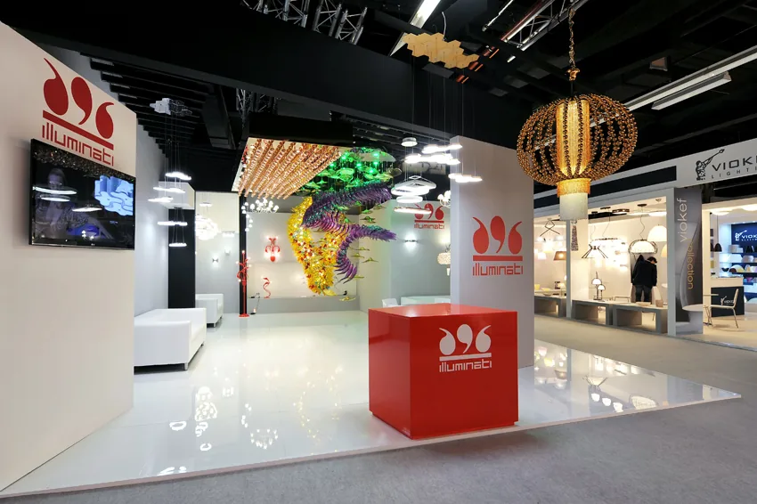 Stand fieristico Illuminati Lighting fiera light&building con installazioni luminose artistiche e design moderno, ideale per fiere del settore illuminazione e design.