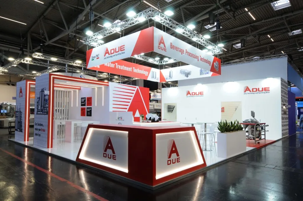 Allestimento stand A DUE spa - Drinktec 2025 di Monaco - Stand fieristico A DUE con design moderno, colori rosso e bianco, illuminazione LED e pannelli informativi su tecnologie per il beverage e il trattamento dell’acqua.